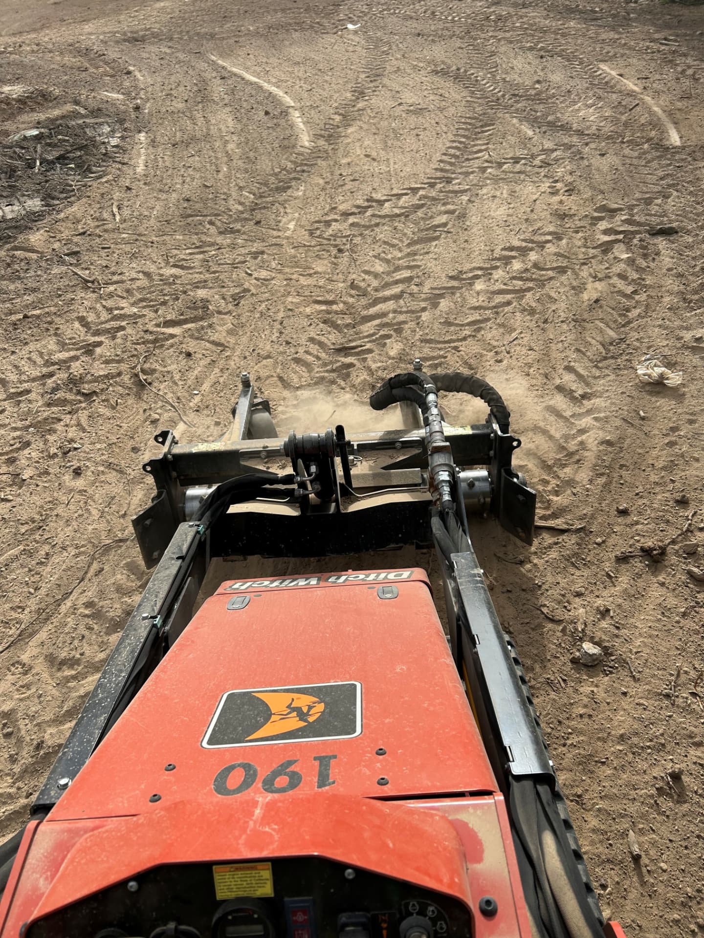 Compact track loader with a soil conditioner attachment grading a dirt lot